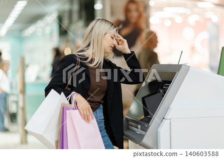 Woman withdrawing cash from ATM after shopping 140603588
