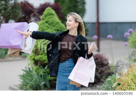Happy woman holding shopping bags walking outdoors Happy woman holding shopping bags walking outdoors 140603590