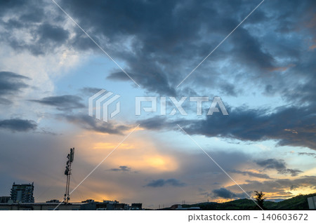 Cloudy sky over city horizon typical evening time sunset lighting with dark heavy clouds and illuminated horizon Cloudy sky over city horizon typical evening time sunset lighting with dark heavy clouds and illuminated horizon 140603672
