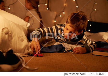 Toy, car and boy child playing on a floor at night in a house for fun, learning or sibling sleepover. Riding, games and kid with racecar in a living room for driving, fantasy or dream with family Toy, car and boy child playing on a floor at night in a house for fun, learning or sibling sleepover. Riding, games and kid with racecar in a living room for driving, fantasy or dream with family 140603683