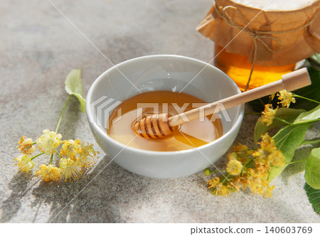 Linden honey bowl with wooden dipper and flowers 140603769