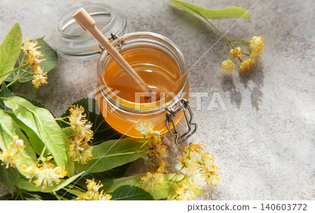 Linden honey jar with wooden dipper and fresh flowers Linden honey jar with wooden dipper and fresh flowers 140603772