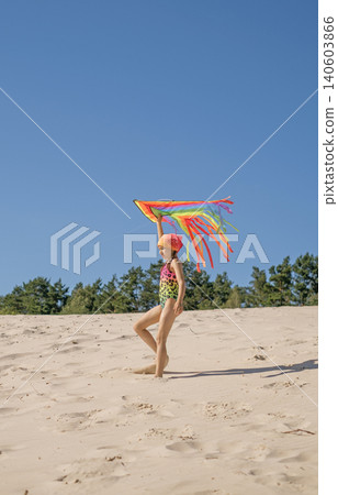 The child holds an airy rainbow kite, catches the wind to launch into the sky. A hot summer day on the beach. Outdoor activities for children The child holds an airy rainbow kite, catches the wind to launch into the sky. A hot summer day on the beach. Outdoor activities for children 140603866