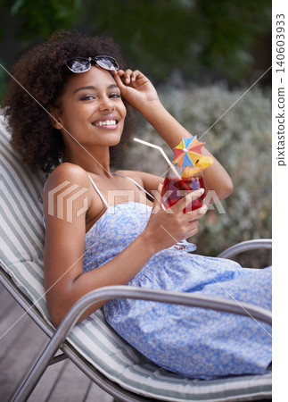 African, woman and sunbathing with cocktail for summer on vacation, tropical drink and sunglasses for time fun. Happy, smile or female person laying on resort deck, comfortable or wellness or liquid 140603933