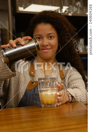 Smiling Brazilian woman bartender pouring beer into a mug at a lively bar, enjoying her work, offering hospitality and refreshing drinks at night Smiling Brazilian woman bartender pouring beer into a mug at a lively bar, enjoying her work, offering hospitality and refreshing drinks at night 140604168