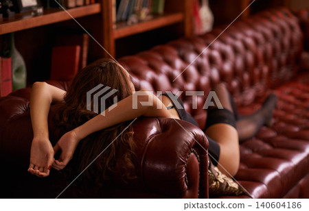Woman, lingerie and sofa for fashion, style and seductive with luxury in living room with bookshelf. Rear view, relaxed and model with underwear for sexy, attractive and sensual on leather couch Woman, lingerie and sofa for fashion, style and seductive with luxury in living room with bookshelf. Rear view, relaxed and model with underwear for sexy, attractive and sensual on leather couch 140604186