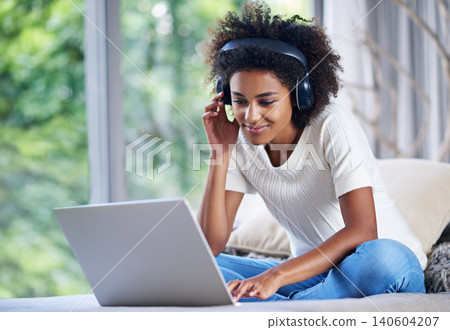 Black woman, headphones and laptop at home for online teaching, e learning and education in living room. Female person, scholar and university student in house for remote class, studying and tuition 140604207