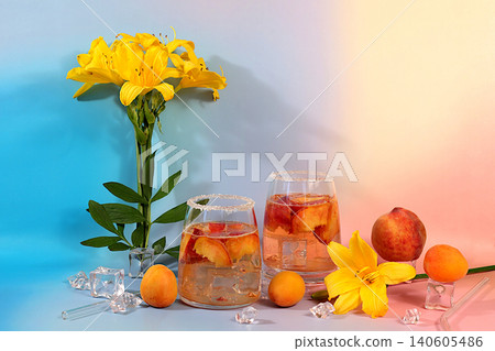 Modern still life with lily flowers and cocktail or tea with apricot, peach and ice cubes on a sunny background,summer party concept, minimalist abstract background for alcoholic beverage presentation Modern still life with lily flowers and cocktail or tea with apricot, peach and ice cubes on a sunny background,summer party concept, minimalist abstract background for alcoholic beverage presentation 140605486