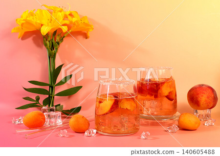 Modern still life with lily flowers and cocktail or tea with apricot, peach and ice cubes on a sunny background,summer party concept, minimalist abstract background for alcoholic beverage presentation Modern still life with lily flowers and cocktail or tea with apricot, peach and ice cubes on a sunny background,summer party concept, minimalist abstract background for alcoholic beverage presentation 140605488
