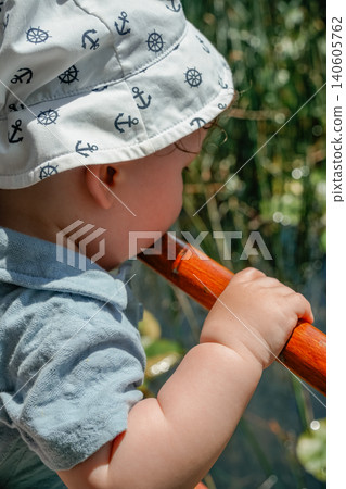 Close up little child holding boat railing looking at reeds during lake travel nature moment 140605762