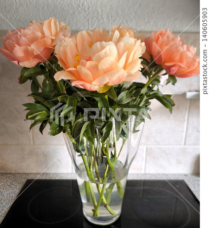 A bouquet of delicate peach peonies in a transparent vase. A bouquet of delicate peach peonies in a transparent vase. 140605903