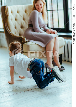 Boy crawls on the floor next to his smiling mother in the room Boy crawls on the floor next to his smiling mother in the room 140607242