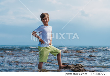 Portrait of happy seven-year-old boy standing in the water by the sea in summer 140607279