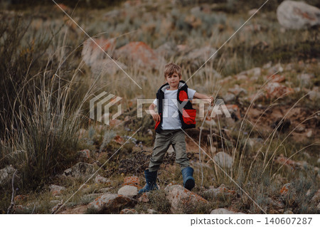 Boy hiker in vest and rubber boots in the mountains 140607287