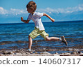 Boy running on the lake shore at sunny day 140607317