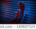 Young woman dancer posing in dark night club interior with neon lights 140607324