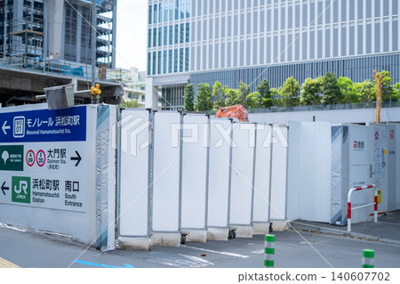 [Hamamatsucho] Scenes of temporary fencing at a redevelopment construction site and directional signs for nearby stations. 140607702