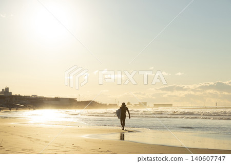 湘南久沼海灘:沐浴在晨光中的衝浪者們沿著海灘漫步。 湘南久沼海灘:沐浴在晨光中的衝浪者們沿著海灘漫步。 140607747
