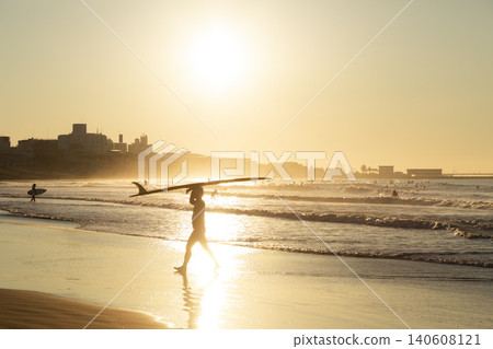 A surfer emerges from the sea, holding up his surfboard, at Kugenuma Beach in Shonan. A surfer emerges from the sea, holding up his surfboard, at Kugenuma Beach in Shonan. 140608121