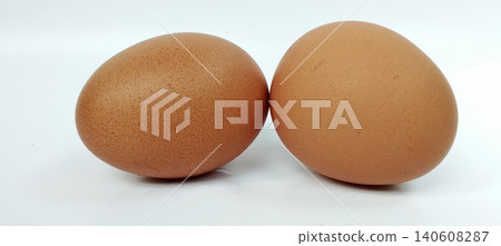Close-up photo of two brown chicken eggs placed on a white background. Close-up photo of two brown chicken eggs placed on a white background. 140608287