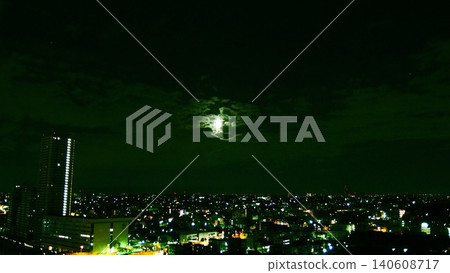 A fantastical moonlit sky; the moon floating between the clouds and the city lights spreading out below. A fantastical moonlit sky; the moon floating between the clouds and the city lights spreading out below. 140608717