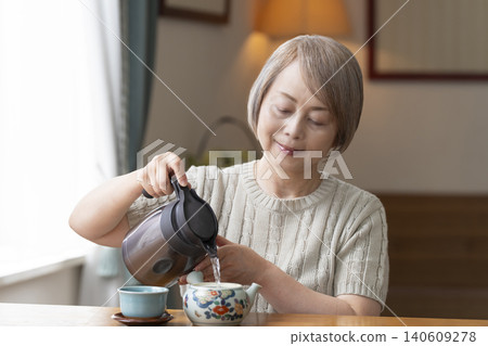 餐廳裡倒茶的老年婦女 140609278