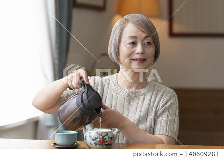 餐廳裡倒茶的老年婦女 餐廳裡倒茶的老年婦女 140609281
