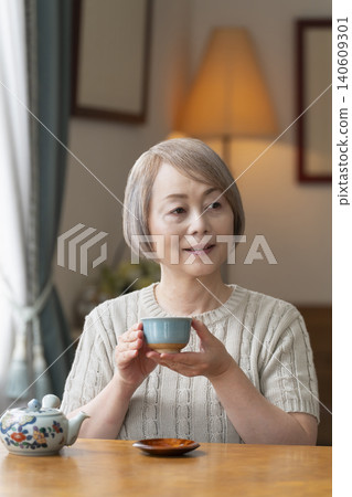 Senior woman pouring tea in the dining room Senior woman pouring tea in the dining room 140609301