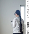 一名女子邊走邊看手機。 140610428