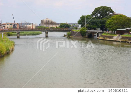 A river landscape featuring the Gamō Ōhashi Bridge over the Ayase River and the site of the former Fujisuke riverbank. A river landscape featuring the Gamō Ōhashi Bridge over the Ayase River and the site of the former Fujisuke riverbank. 140610811