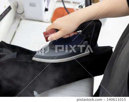 A scene of ironing with steam rising from the iron. A scene of ironing with steam rising from the iron. 140611015