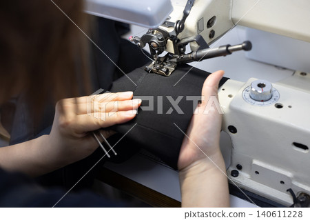 Hand of a woman operating a sewing machine Hand of a woman operating a sewing machine 140611228