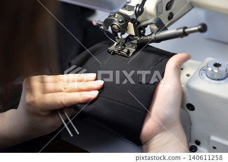 Hand of a woman operating a sewing machine Hand of a woman operating a sewing machine 140611258