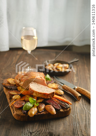 Dinner plate with roasted meat, vegetables, and glass of white wine on wooden table Dinner plate with roasted meat, vegetables, and glass of white wine on wooden table 140611316