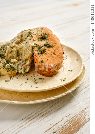Grilled meat served with creamy mushroom sauce and herbs on simple plate at kitchen table Grilled meat served with creamy mushroom sauce and herbs on simple plate at kitchen table 140611331