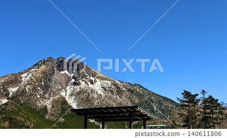 The rugged rock face and remaining snow of Mount Nikko-Shirane stand out against the blue sky. 140611806