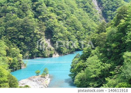 A view of the turquoise-blue lake of Sumatakyo Gorge, spanned by a dream suspension bridge. A view of the turquoise-blue lake of Sumatakyo Gorge, spanned by a dream suspension bridge. 140611918