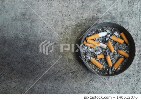 Ashtray with cigarette butts and ashes on gray surface Ashtray with cigarette butts and ashes on gray surface 140612076
