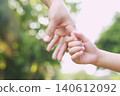 Adult hand holding child's hand in sunlight outdoors 140612092