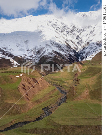 Snow-capped peaks rise above green valleys, vertical view Snow-capped peaks rise above green valleys, vertical view 140612163