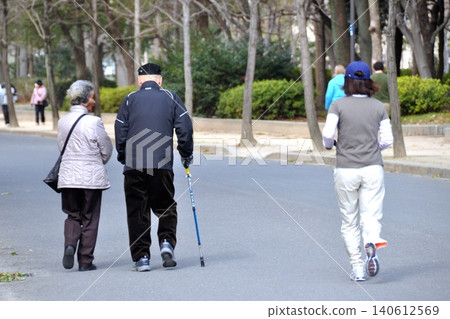 Senior couple walking with a cane 140612569