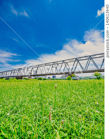 A Keisei train crossing a railway bridge against a blue sky and green rice fields. A Keisei train crossing a railway bridge against a blue sky and green rice fields. 140613640