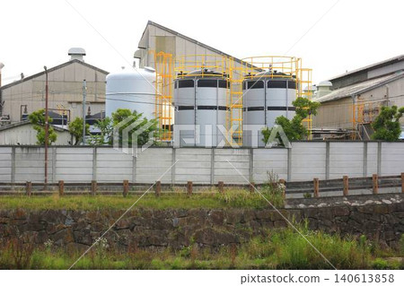 Industrial plant facilities lined up beyond the seawall and road. 140613858