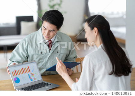 A housewife and a construction worker discussing renovation plans. 140613981