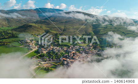 Aerial view of mountain village in Catalonia surrounded by low clouds and green hills near Pyrenees mountains in Spain Aerial view of mountain village in Catalonia surrounded by low clouds and green hills near Pyrenees mountains in Spain 140614908