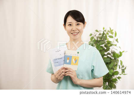 一名護士拿著用藥記錄簿和藥袋。 一名護士拿著用藥記錄簿和藥袋。 140614974