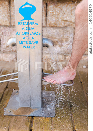 Sitges, Spain, 10 May 2026: Beach foot washing station with water conservation message at seaside resort 140614979