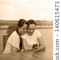 Two girls using a phone 140615471
