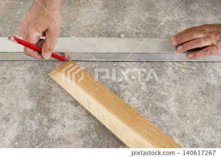 Worker hands measuring and marking layout for Italian herringbone parquet flooring installation Worker hands measuring and marking layout for Italian herringbone parquet flooring installation 140617267