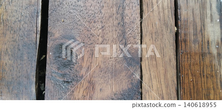 A close-up photo showing the surface of an old wooden board with its natural texture, clear wood grain, and rich, distinctive dark brown color. A close-up photo showing the surface of an old wooden board with its natural texture, clear wood grain, and rich, distinctive dark brown color. 140618955